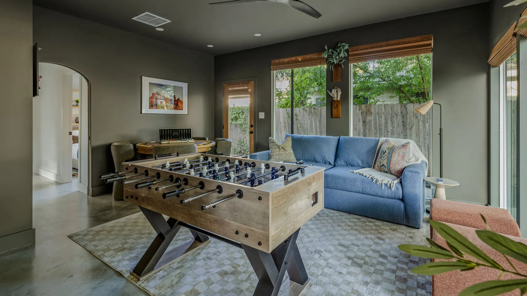 The game room, olive green on every wall, with a foosball table, a blue sleeper sofa and a card table by the door